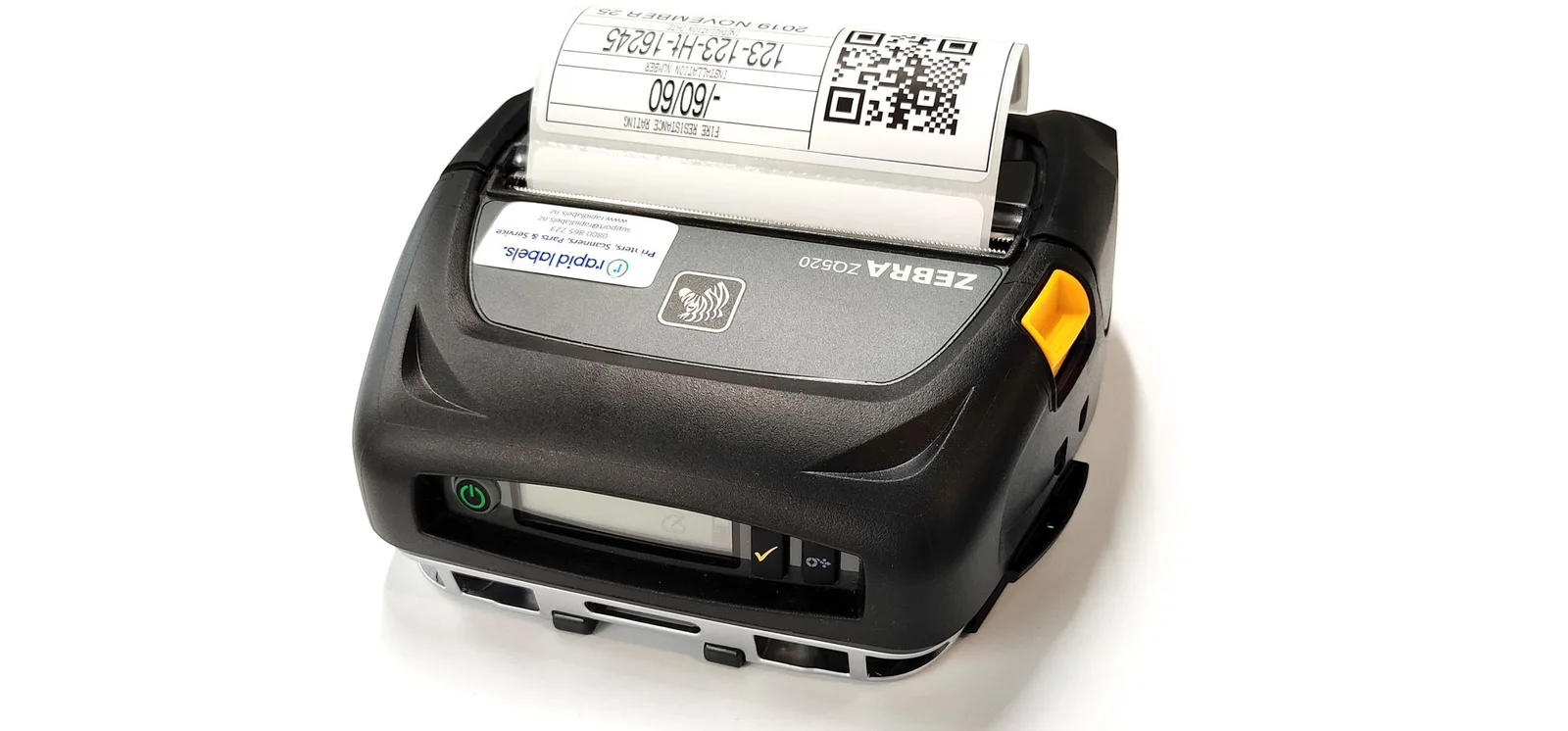 A Zebra Bluetooth label printer printing a QR-coded penetration label with its installation number and fire resistance rating